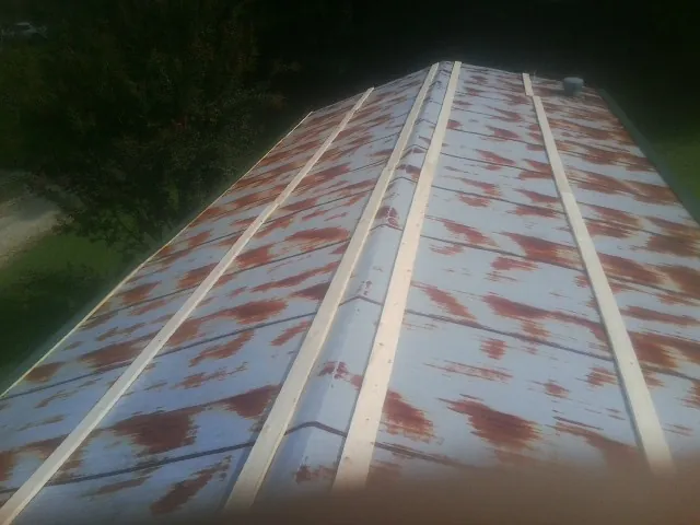Rusted metal roof panels with new wood purlins before replacement — Storm Damage Roof Repair in Merrill by Roofing Brothers